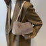 Model carrying a khaki mini fluffy shearling baguette bag on the shoulder, easy for commuting and weekends.
