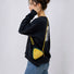 A model wearing a yellow triangle mini bag as a crossbody, highlighting the geometric style impact.