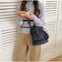Front view of a model carrying the black nylon bag crossbody style.