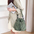 Model wearing the olive green nylon bucket bag with a beige coat.