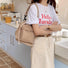 Model posing with the khaki nylon bucket bag in a modern kitchen setting.
