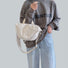 Model holding the off-white nylon bag, showcasing its soft slouchy shape and top handle.