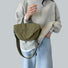 Model holding the olive green crinkle nylon bag as a casual carry.