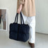 Person holding a black padded nylon tote bag with two top handles.
