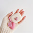 Hands holding a pink heart airpods case, easy to carry for commutes and travel; for office.