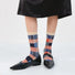 Model wearing a pair of Plaid Patchwork Socks in beige, great for daily wear and lounging.