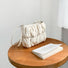 Close-up of beige pleated cloud bag with adjustable strap on a wooden table, ideal for errands.