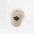 Beige corduroy baseball cap featuring a black plush flower embroidery.