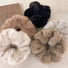 Assortment of five plush faux fur scrunchies in black, beige, tan, brown and grey.