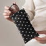Close-up view of hands holding the black polka dot PU leather glasses pouch with metal spring ring.