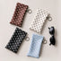 Studio group display of polka dot glasses cases in black, brown, white, and light blue beside a pair of black sunglasses.