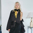 Model wearing black and yellow polka dot knit scarf over a vest.