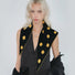 Model wearing black and yellow reversible polka dot knit triangle scarf.