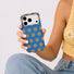 Close-up of a model holding the blue silicone case with orange polka dots.