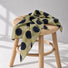 Soft green polka dot silk scarf displayed on a wooden stool.