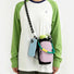 Front view of a model styling the pastel pink utility bottle bag as a crossbody bag with a phone hanging.