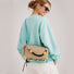Model wearing the khaki reversible nylon utility bag as a crossbody.