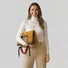 Model holding the high-capacity reversible tote.It is folded into a sleek clutch, demonstrating its multi-functional silhouette.