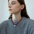 Model wearing red resin bead necklace with artificial pearl drop, elegant jewelry styling