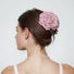Woman with dark hair in a bun, adorned with a large, soft pink polyester rose hair claw.