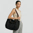 Model carrying the black canvas tote bag as shoulder style.