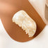 Folded view of Shell hair claw in cream marble, ideal for quick updos and ponytails.