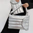 Model carrying a silver polyester bag handheld, great for daily carry and travel.