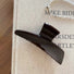 Flat lay of Sleek Curved Hair Claw in dark brown, great for everyday styling and gifting.