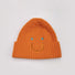 Front view of Smiley Ribbed Knit Beanie in orange. Vibrant fall color with a whimsical smile embroidery.