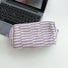 Front view of purple striped knitted makeup bag, ideal for travel makeup and toiletries.