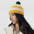 Model wearing the yellow and white striped beanie with a green pompom.