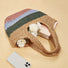 Stripe rattan straw bag with pink, blue, green, and natural stripes, holding white flowers and a book.
