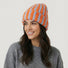 Model wearing Striped Fluffy Knit Beanie in orange blue. Vibrant striped pattern in a soft, snug fit.