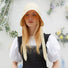 Model wearing the cream yellow ribbon hat in a bright outdoor garden setting.