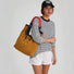 Model shoulder-carrying the corduroy tote bag, styled with a striped long-sleeve top and white shorts, outdoor casual look.