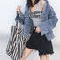 Woman holding a large white and black thin stripe canvas tote bag with shoulder strap.