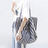 Model styling navy blue striped tote over shoulder, durable canvas fabric ideal for students and campus life.