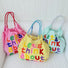 Three cotton "Think About Earth" tote bags in pink, yellow, and mint green with colorful embroidered text.