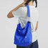 A model wearing the blue Breezy Trail Bag, showcasing the adjustable crossbody strap by knotting.