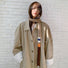 Model wearing a polyester scarf in beige and khaki and brown, easy for weekend styling and gifting.