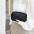 Model holding a black makeup bag in hand, easy to carry for travel and errands.