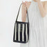 Model holding the small woven striped raffia bucket bag.