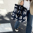 Model carring a black Alphabet Canvas Tote Bag With Double Strap, easy for commuting and weekends.