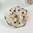 Angled view of Black Trim Satin Scrunchie, ideal for quick updos and ponytails.