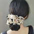 Model wearing satin scrunchie with white background, black heart pattern and black trim.