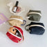 Four small canvas makeup bags in red, beige, olive green, and black, with white zippers and carry loops.