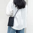 Black PU leather woven crossbody bag with long strap, worn by a person in a white shirt.