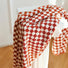 Red and white checkerboard cotton bath towel draped over a white stand.
