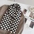 Close-up of a plaid scarf in black and white over a brown blazer, easy for weekend styling and gifting.