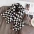 Angled view of Black and white checkerboard wool blend scarf draped over a brown blazer, easy for travel.